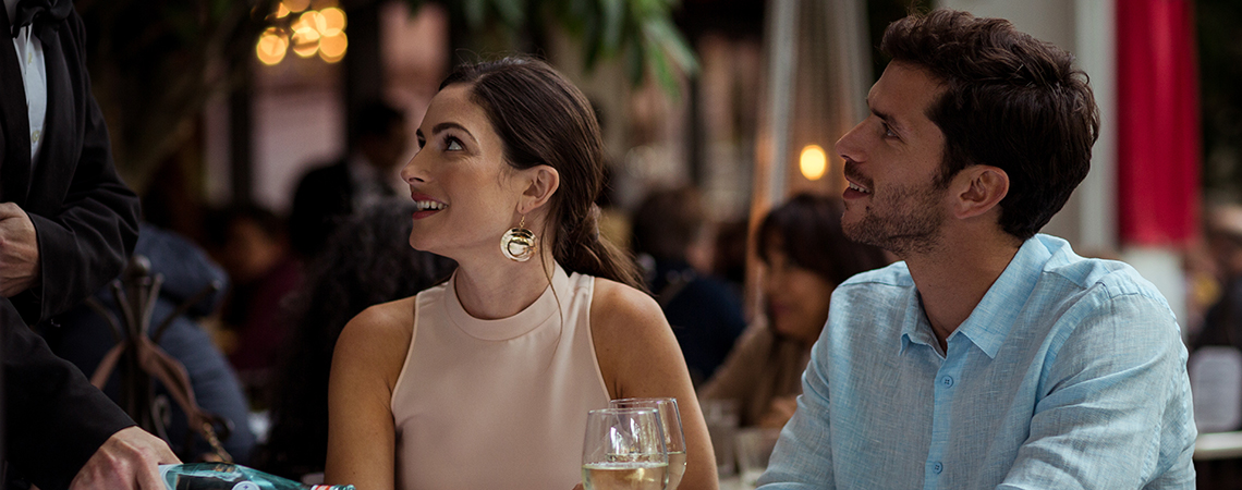 A couple looks up at a server and smiles