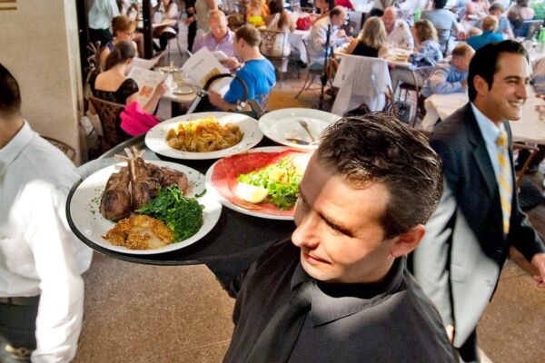 A server carries a tray with plates of food