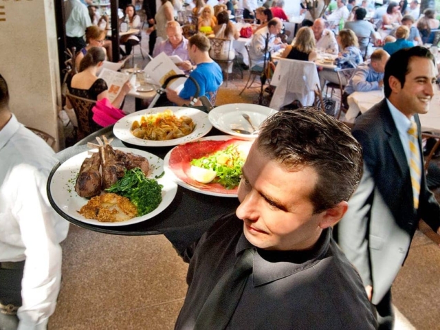 A server carries a tray with plates of food