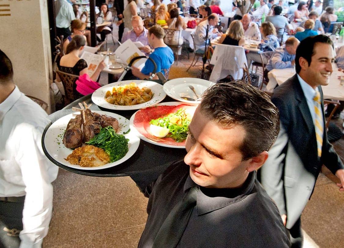 A server carries a tray with plates of food