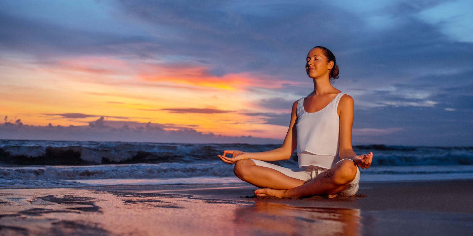Woman in relaxed yoga pose on the beach.